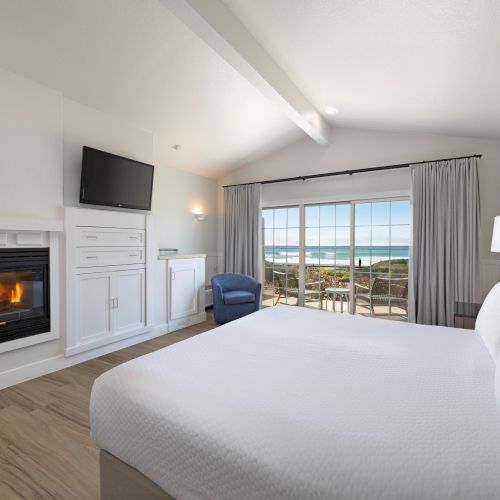 A modern living area with a built-in fireplace, a light blue couch, a large wall-mounted TV, and a cozy grey rug in a bright, airy room.