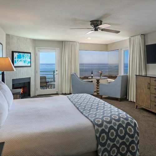 A stylish hotel-style bedroom with a large bed, nightstands, soft lighting, a seating area, and a balcony view.